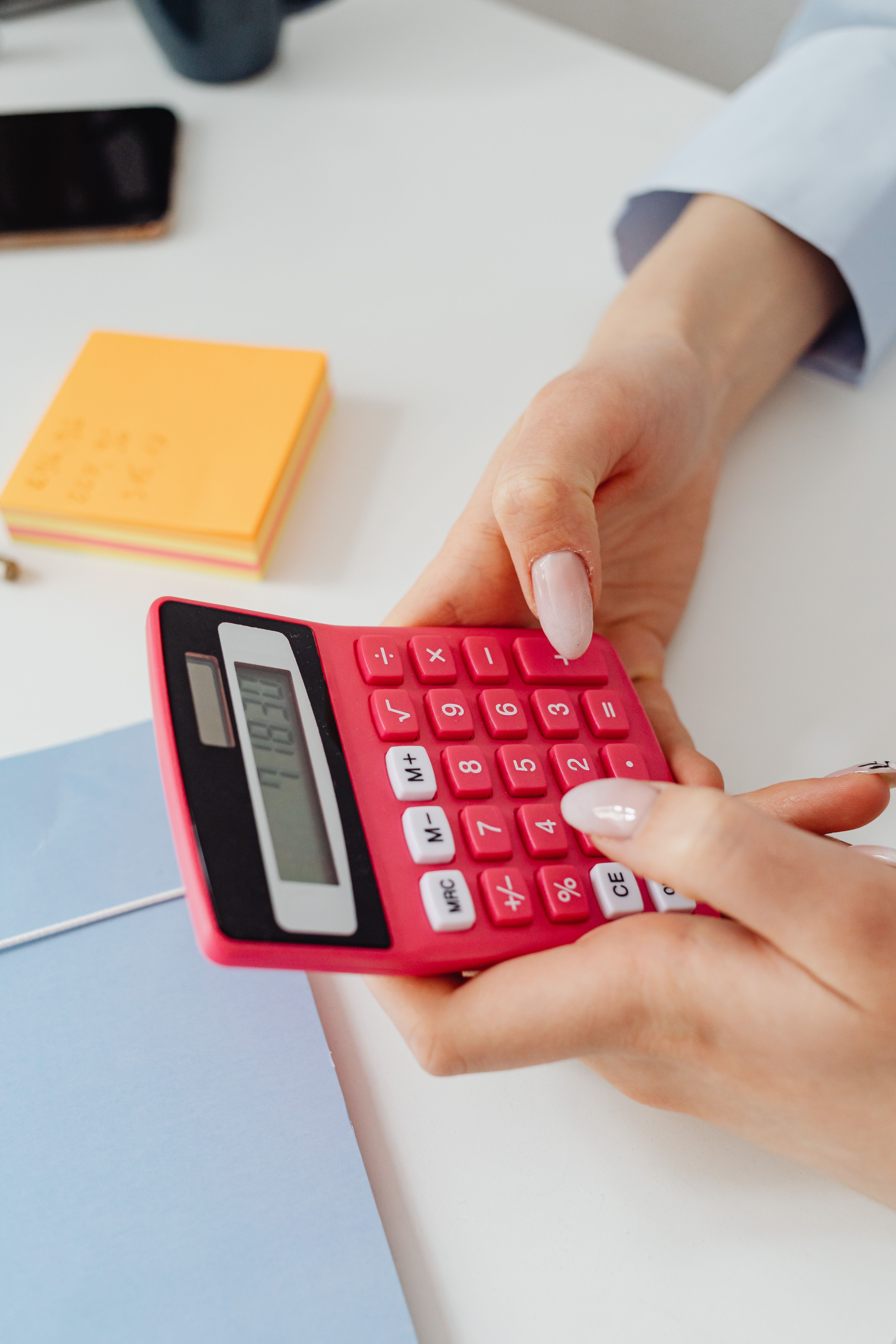 Primer plano de manos usando una calculadora roja sobre un escritorio para hacer cálculos financieros
