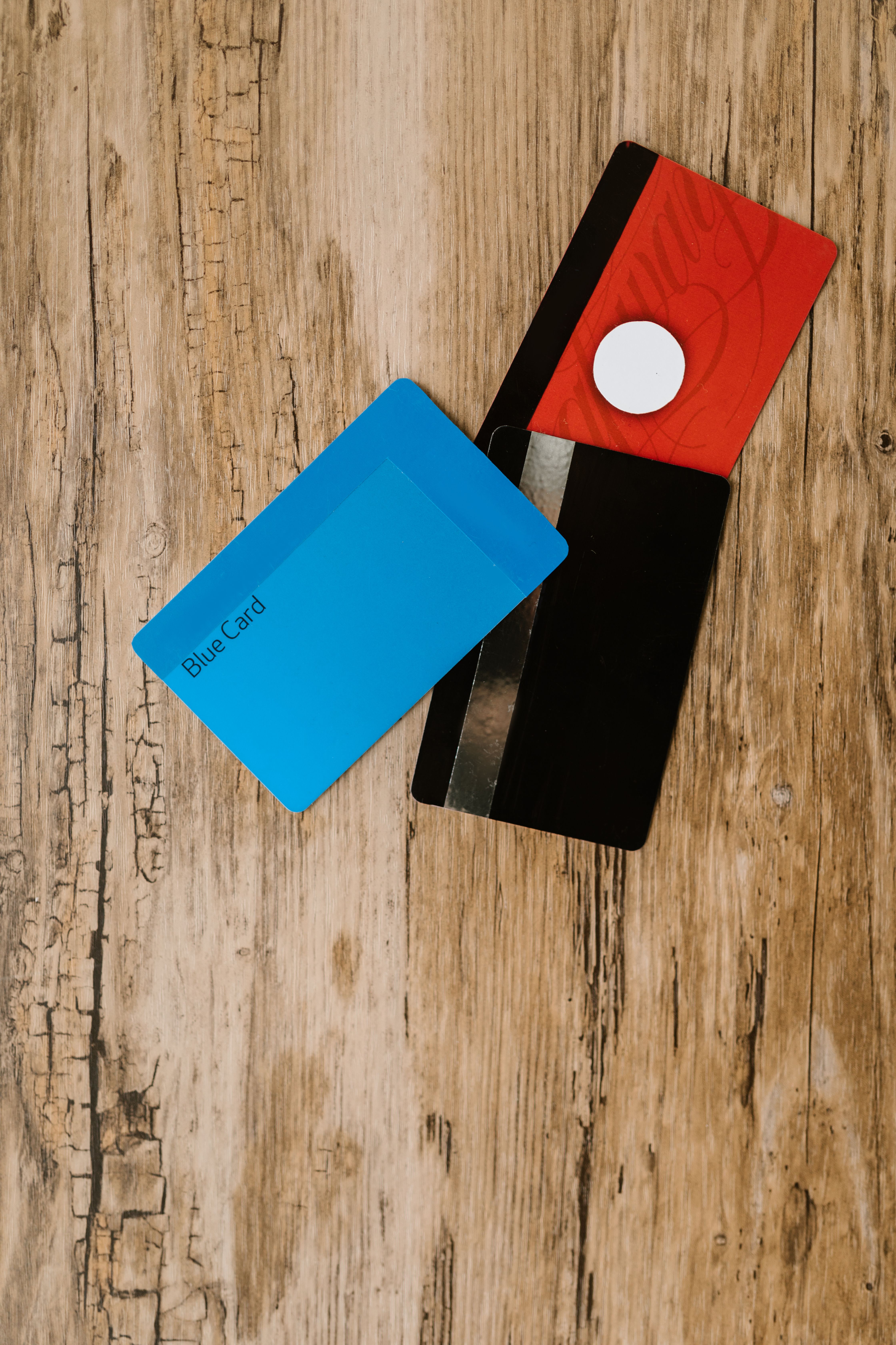 Dos tarjetas genéricas, azul y roja, sin logos, sobre una mesa de madera